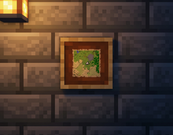 An explored Minecraft map mounted in a wooden item frame on a stone-brick wall, lit by warm lantern light.